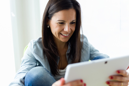 Portrait of beautiful young woman using her digital tablet at home.の写真素材