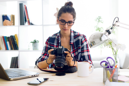 Portrait of young woman photographer checking previews on camera in the studio.