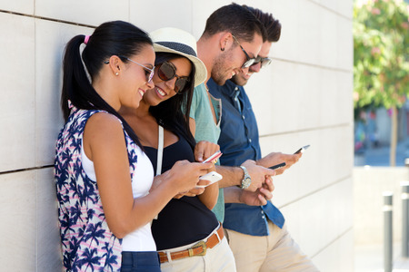Outdoor portrait of group of friends having fun with smartphones.の写真素材