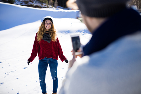 Portrait of happy young couple taking photos over winter background.の写真素材