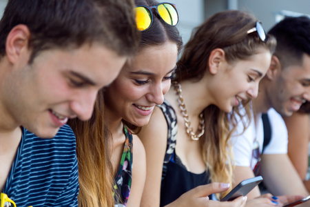 Portrait of group of students having fun with smartphones after class.の写真素材