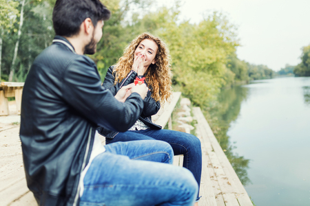 Portrait of man showing an engagement ring diamond to his girlfriend in the park.の写真素材