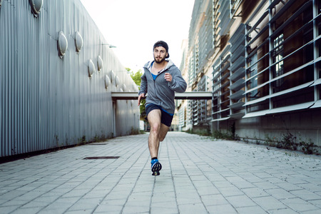 Portrait of young man running in the street.