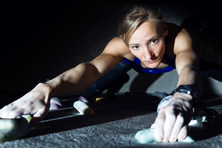 Portrait of fit woman rock climbing indoors at the gym.の写真素材