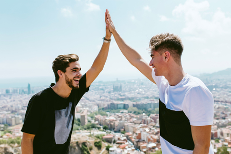 Portrait of two young men looking at the views form the top of a mountain.