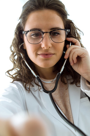 Portrait of female doctor checking patient heartbeat using stethoscope.の写真素材