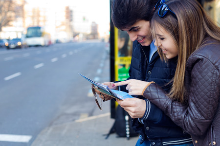 Portrait of young tourist couple in town holding a map.の写真素材