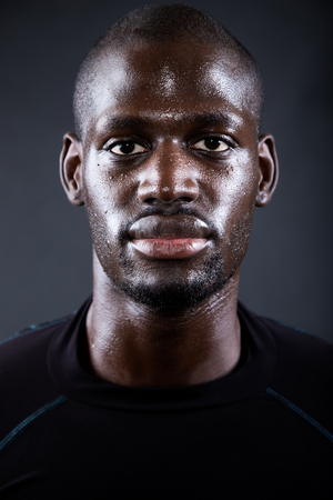 Portrait of athletic man running in black background.