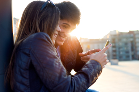 Portrait of young couple of tourist in town using mobile phone.の写真素材