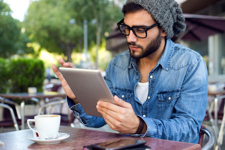 Outdoor portrait of modern young man with digital tablet in the street.