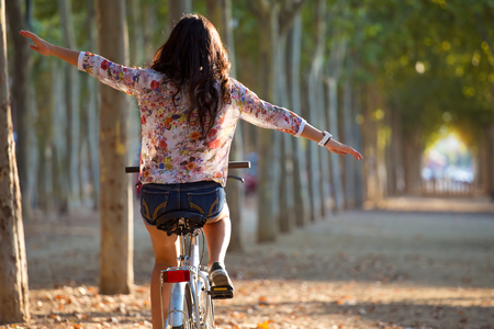 Outdoor portrait of pretty young girl riding bike in a forest.の写真素材