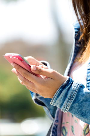 Portrait of mobile phone in a woman's hand. Outdoor image.の写真素材