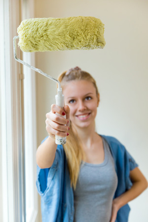 Portrait of young beautiful woman painting her new home.の写真素材