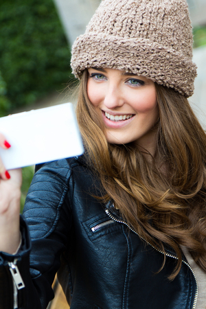 Portrait of Cute brunette woman taking photo of herself on the streetの写真素材