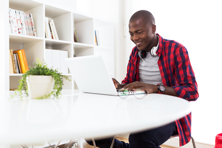 Portrait of handsome young man using his laptop at home.の写真素材