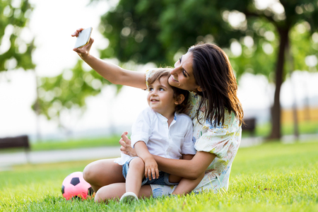 Portrait of beautiful young mother with her son taking a selfie in the park.の写真素材
