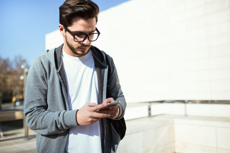 Portrait of handsome young man using his mobile phone in the street.の写真素材