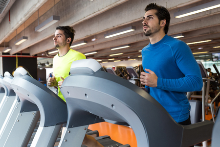 Portrait of two handsome young men doing cardio training in gym.の写真素材