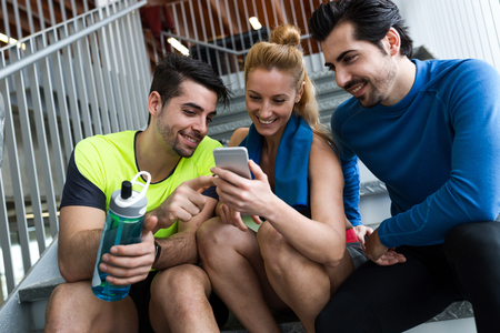 Portrait of group of sporty people using mobile phone in gym.の写真素材