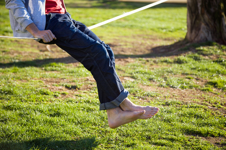 Detail of the legs of a man walking on slackline in the park.の写真素材