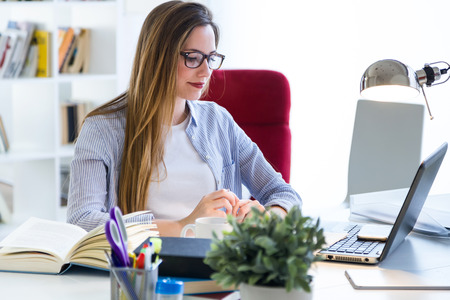 Portrait of beautiful young woman working with laptop in her office.の写真素材