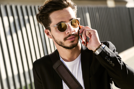 Portrait of handsome young man using his mobile phone in the street.の写真素材
