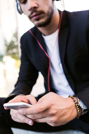 Portrait of handsome young man listening to music with mobile phone in the street.の写真素材