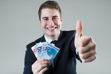 Portrait of young man in formalwear holding money.の写真素材