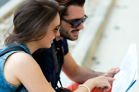 Portrait of young tourist couple in town holding a map.の写真素材