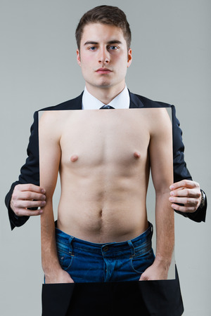 Portrait of businessman in black suit holding a photo of a naked male torso.の写真素材