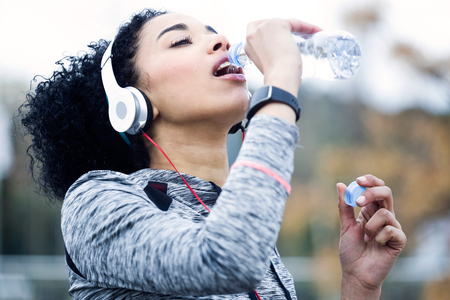 Portrait of fit and sporty young woman drinking water.