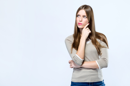 Portrait of beautiful young woman thinking over white background.の写真素材