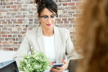 Portrait of beautiful young businesswoman using her mobile phone in the office.の写真素材
