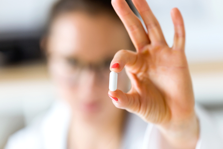 Portrait of female doctor giving you a pill.の写真素材