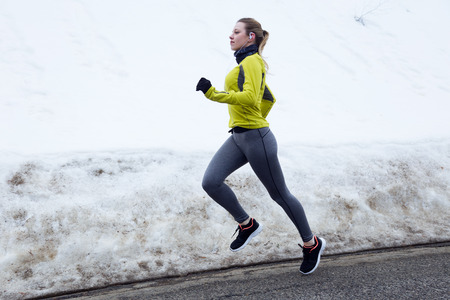 Outdoor portrait of young woman stretching and preparing for running on the road.の写真素材