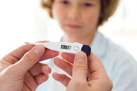 Portrait of doctor measuring the temperature to the girl in the office.の写真素材