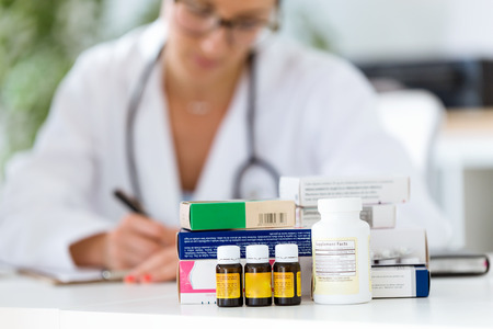Portrait of beautiful female pharmacist holding jar of pills in hands.の写真素材