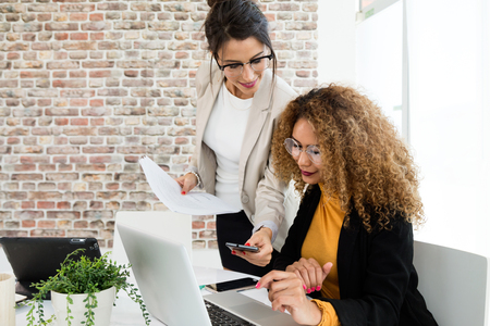 Portrait of two businesswoman working with laptop in her office.の写真素材