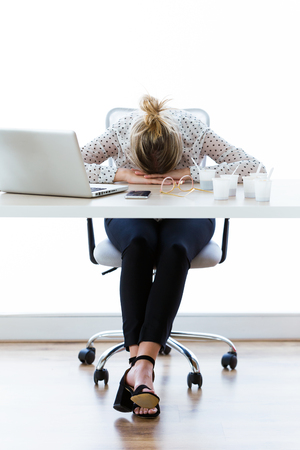 Shot of tired young businesswoman sleeping on her desk in the office.の写真素材