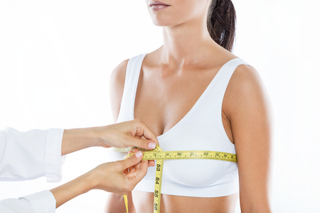 Portrait of doctor with measure tape measuring the size of the patient's breast.の写真素材