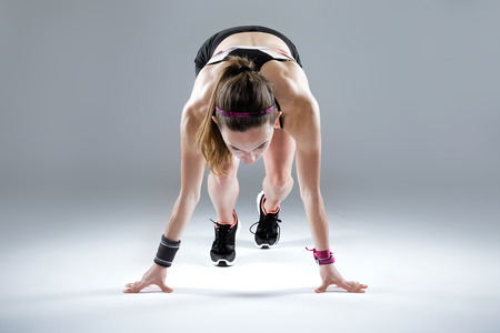 Portrait of fit and sporty young woman preparing for a run on white background.の写真素材