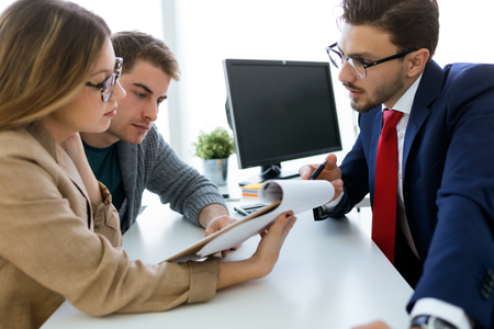 Portrait of business young man explaining terms of contract to his clients in the office.の写真素材