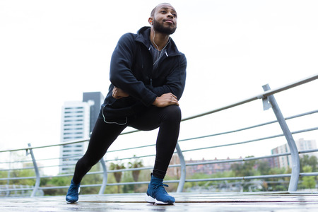 Portrait of fit and sporty young man doing stretching in the city.の写真素材