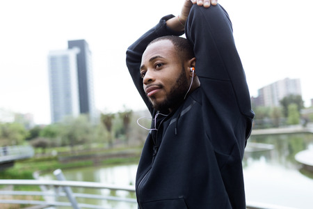 Portrait of fit and sporty young man doing stretching in the city.の写真素材