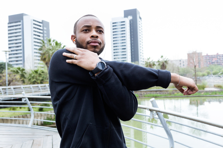 Portrait of fit and sporty young man doing stretching in the city.