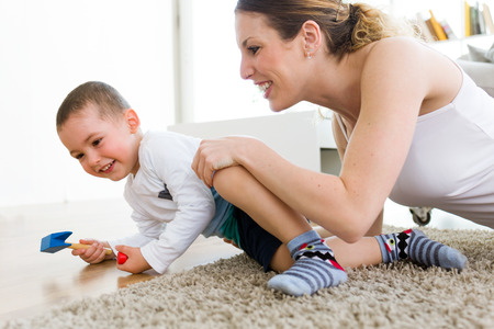 Portrait of beautiful young mother and her son having fun at home.の写真素材