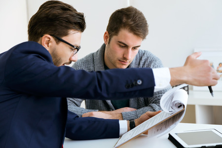 Portrait of business young man explaining terms of contract to his client in the office.の写真素材