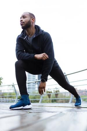 Portrait of fit and sporty young man doing stretching in the city.の写真素材