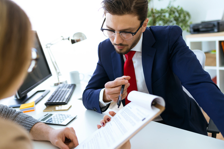 Portrait of business young man explaining terms of contract to his clients in the office.の写真素材