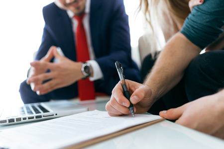 Portrait of beautiful young couple signing financial contract in the office.の写真素材